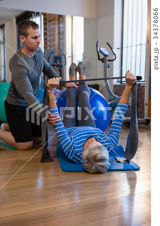 Physiotherapist assisting senior woman in performing exercise with resistance band Physiotherapist assisting senior woman in performing exercise with resistance band 34378066