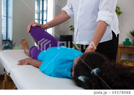 Physiotherapist giving leg massage to a girl patient Physiotherapist giving leg massage to a girl patient 34378088