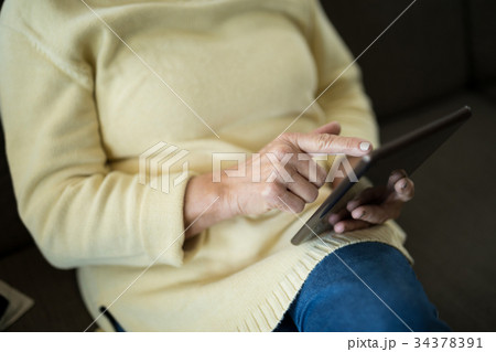 Senior woman using digital tablet on sofa Senior woman using digital tablet on sofa 34378391