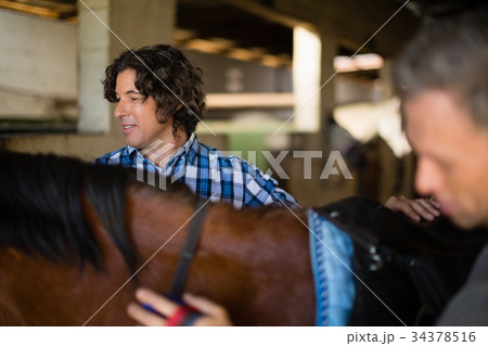 Man grooming the horse in the stable 34378516