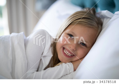 Smiling girl lying on bed in bedroom 34378518