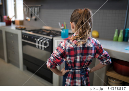 Smiling girl posing wearing an apron in the kitchen Smiling girl posing wearing an apron in the kitchen 34378817