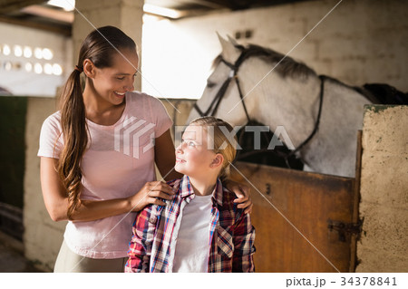 Sisters talking while standing against horse 34378841