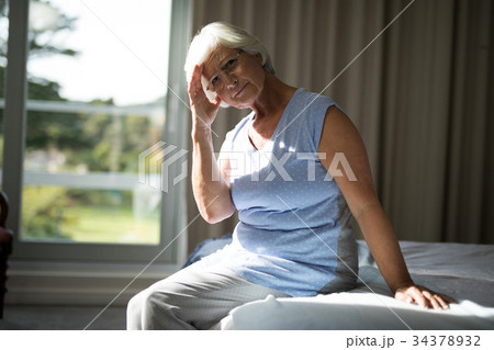 Tense senior woman sitting on bed in bedroom Tense senior woman sitting on bed in bedroom 34378932