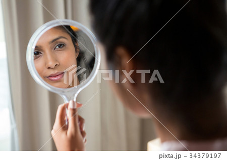 Woman reflecting on hand mirror Woman reflecting on hand mirror 34379197