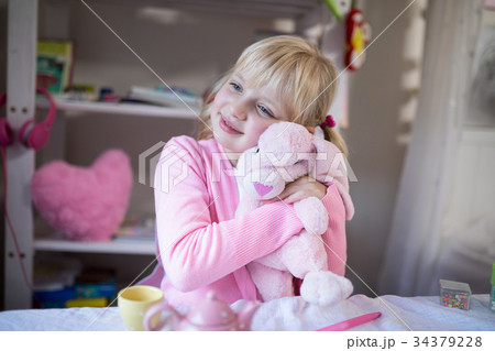 Smiling girl playing with a teddy bear and toy kitchen set Smiling girl playing with a teddy bear and toy kitchen set 34379228