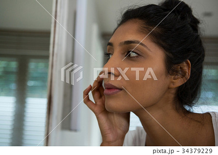 Woman touching face by mirror Woman touching face by mirror 34379229