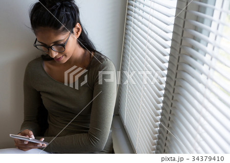 Woman using phone by window 34379410
