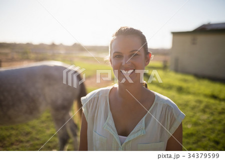 Portrait of jockey standing on field at barn Portrait of jockey standing on field at barn 34379599