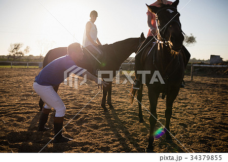 Trainer training friends in riding horse at barn Trainer training friends in riding horse at barn 34379855