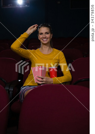Woman having popcorn and drinks while watching movie in theatre Woman having popcorn and drinks while watching movie in theatre 34379856