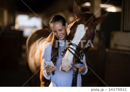Female vet using mobile phone while standing by horse Female vet using mobile phone while standing by horse 34379932