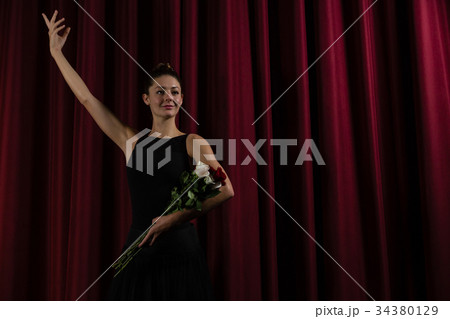 Ballerina posing with flower bouquet on stage Ballerina posing with flower bouquet on stage 34380129