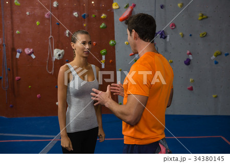 Friends talking while standing by climbing wall at gym Friends talking while standing by climbing wall at gym 34380145