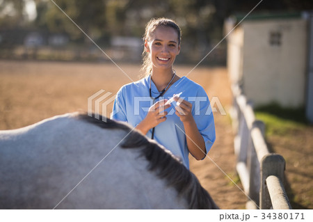 Portrait of smiling female vet holding syringe 34380171