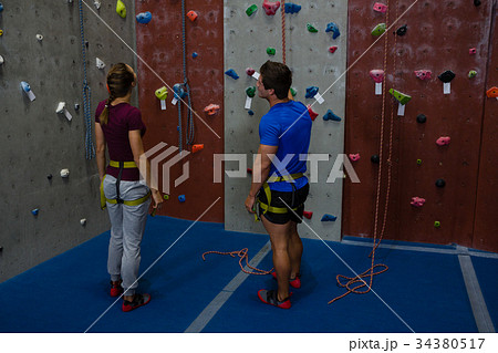 Male trainer guiding woman in climbing wall at gym Male trainer guiding woman in climbing wall at gym 34380517