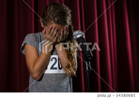 Girl covering her face with hand on stage 34380685