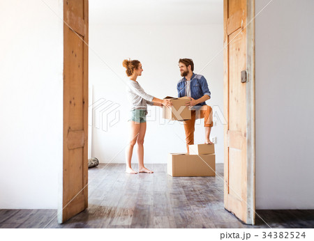 Young couple moving in new house, holding boxes. 34382524