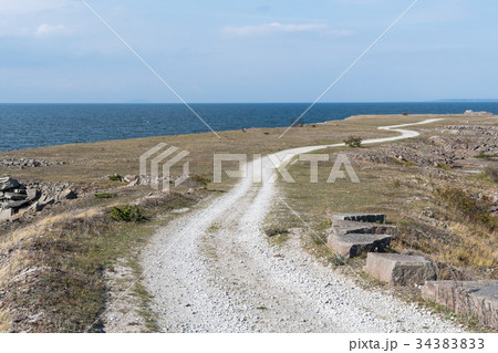 Winding gravel road in a coastal landscape 34383833