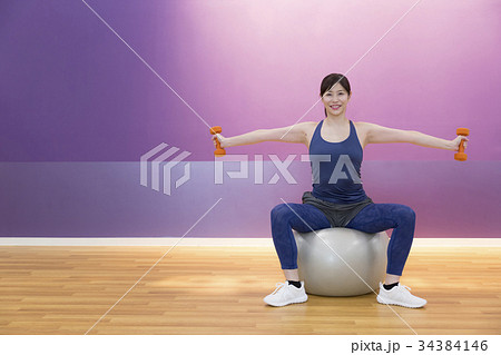 バランスボールに乗ってダンベル体操をする女性 バランスボールに乗ってダンベル体操をする女性 34384146