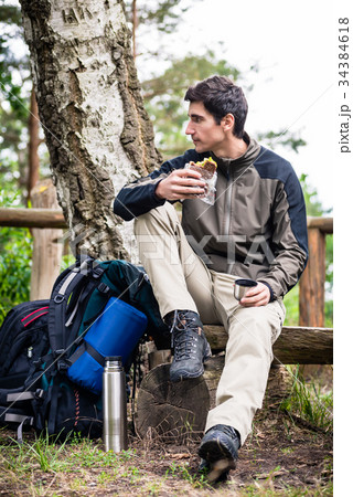 Hiker taking food break in shade of tree 34384618