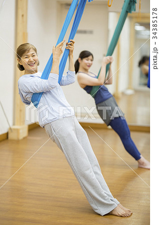 シニア女性にエアリアルヨガを指導するトレーナー 34385178