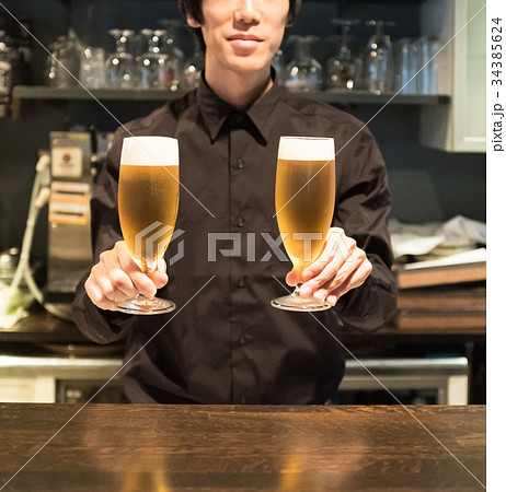 ビールを差し出すバーテンダー 34385624