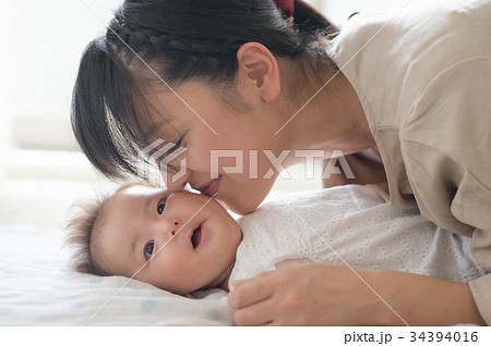 赤ちゃんの頬にキスする母親の写真素材