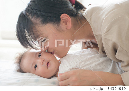 赤ちゃんの頬にキスする母親の写真素材