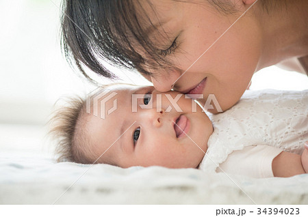 赤ちゃんの頬にキスするママ の写真素材
