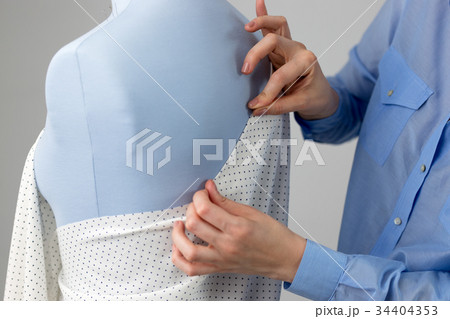 Seamstress measuring beautiful fabric on blue 34404353