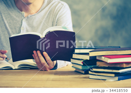 a man reading a book and making his notes a man reading a book and making his notes 34418550