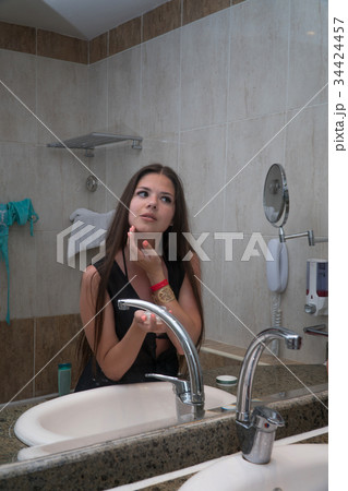 girl smears face with cream in the bathroom 34424457
