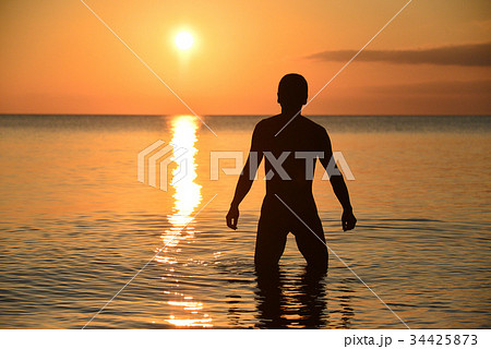夕陽と夕焼けをバックに海にヌードで立っている男の人をシルエットで撮影の写真素材 夕陽と夕焼けをバックに海にヌードで立っている男の人をシルエットで撮影の写真素材