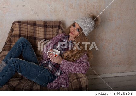 a girl sits in a chair with cup of coffee or tea 34429358