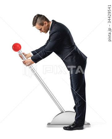 A businessman stands at a large lever with a red 34429541
