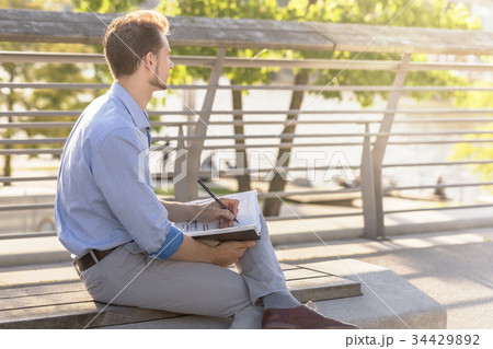 Businessman with notepad on bench Businessman with notepad on bench 34429892