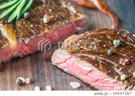 Beef steak with fresh rosemary on the wooden board Beef steak with fresh rosemary on the wooden board 34447167