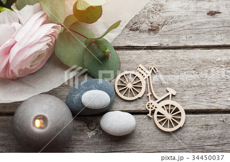 Pink ranunculus, pebbles and lit candles 34450037