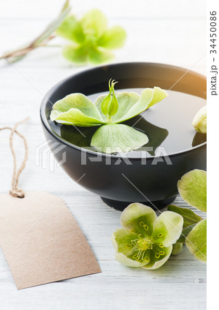 Green flowers, bowl and lit candle 34450086