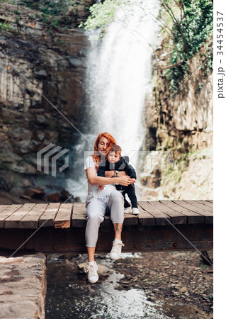 Mom and little son are sitting on the bridge Mom and little son are sitting on the bridge 34454537
