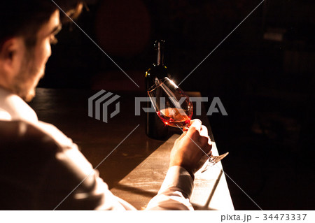 The handsome man is holsing a glass of red wine in 34473337