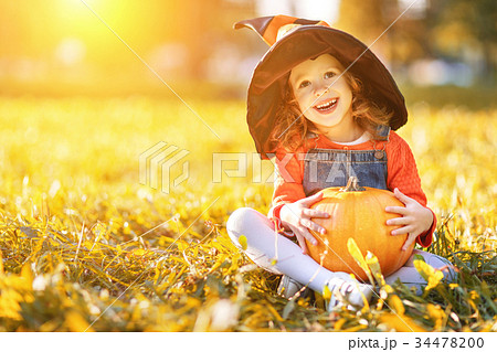child girl with pumpkin outdoors in halloween 34478200