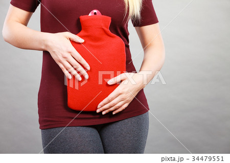 Girl having stomach ache, holding hot water bottle Girl having stomach ache, holding hot water bottle 34479551