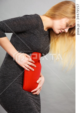 Girl having stomach ache, holding hot water bottle Girl having stomach ache, holding hot water bottle 34479557