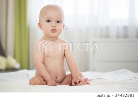 Cute naked baby boy sitting on bed Cute naked baby boy sitting on bed 34482983