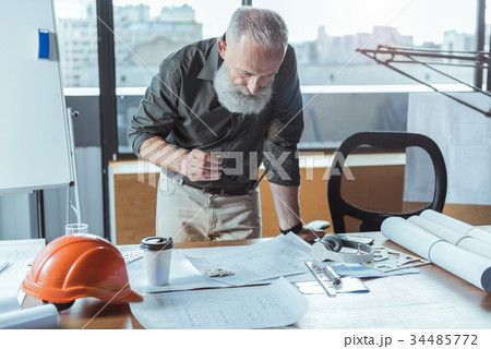 Professional old man is working in office with 34485772