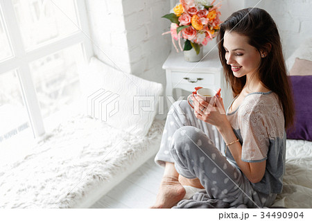 Smiling young woman with cup of aromatic tea Smiling young woman with cup of aromatic tea 34490904