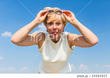 Funny senior woman sticking her tongue out while 34493925