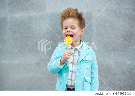 Fashion kid with lollipop near gray wall 34494110